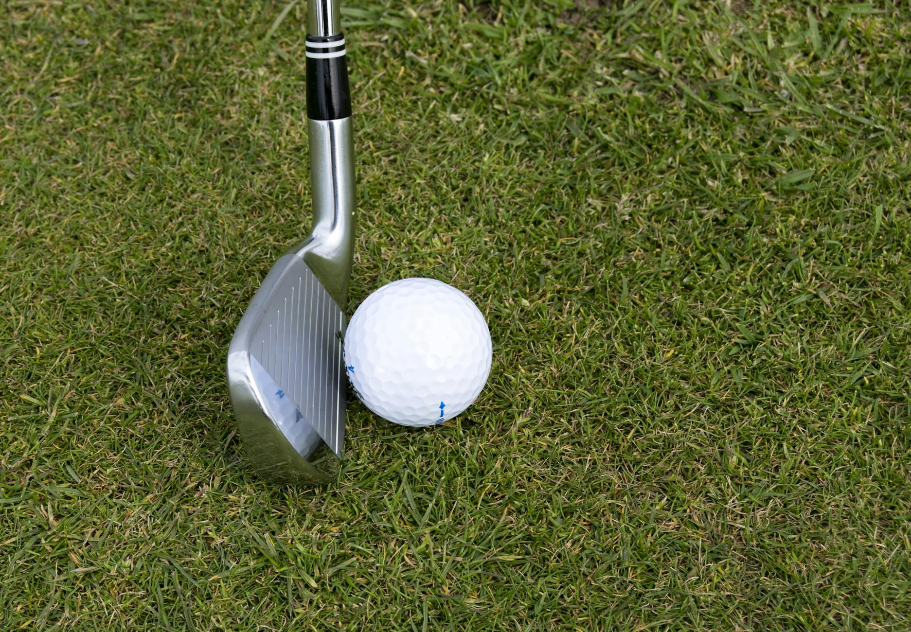 silver wedge golf club beside ball
